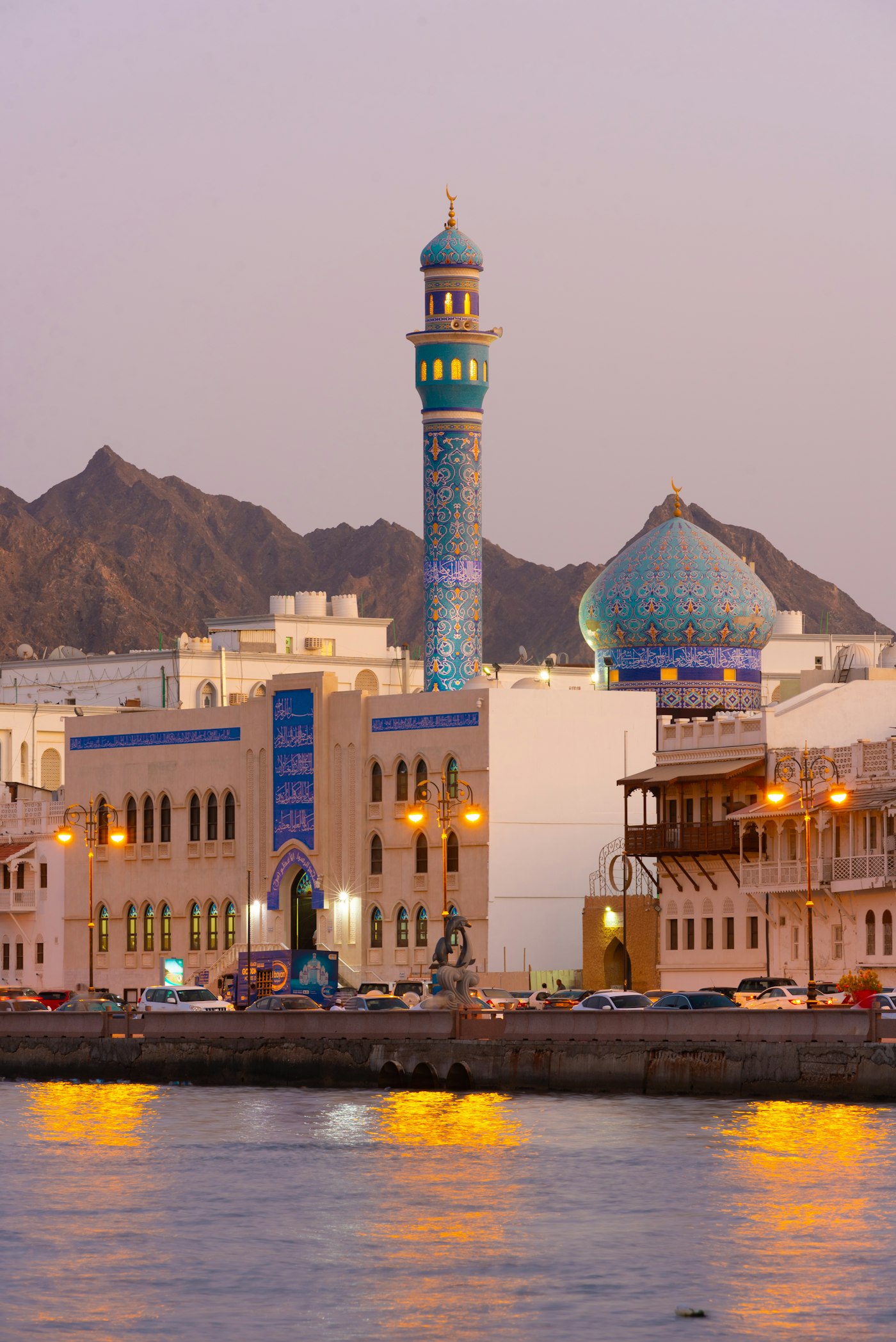 Mutrah waterfront in Muscat at dusk, mountains behind the corniche